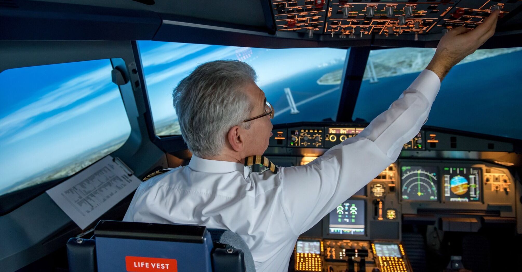 Pilot in uniform operating a flight simulator cockpit