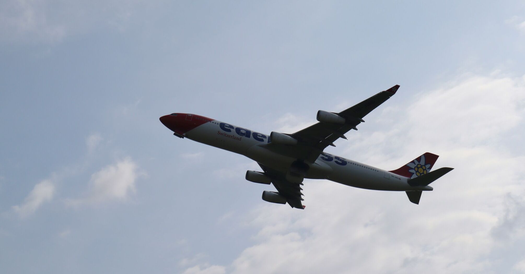 A large jetliner flying through a cloudy blue sky