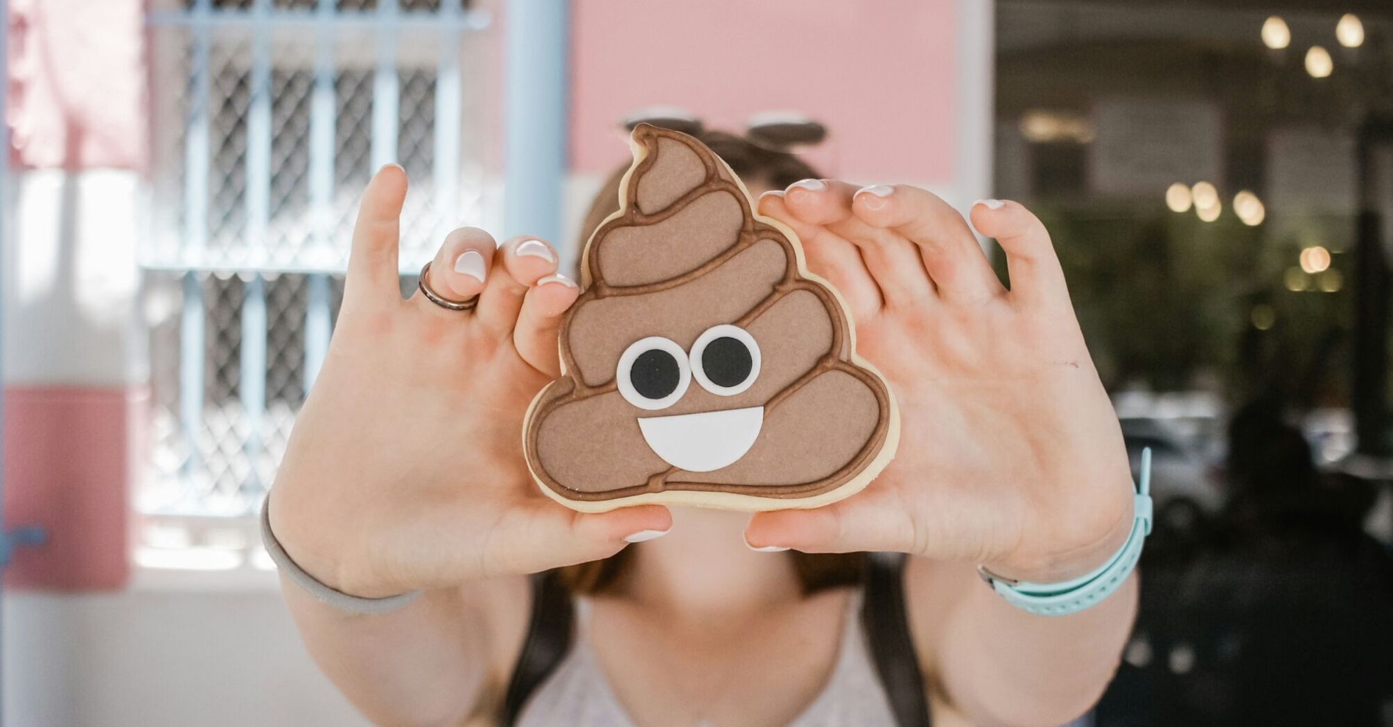 Person holding a cookie shaped like the poop emoji