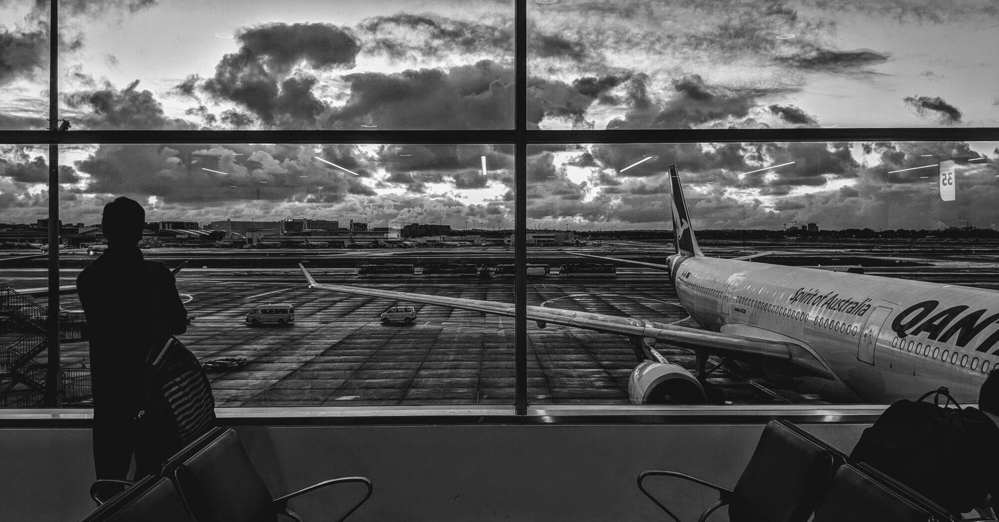 Grayscale photography of man standing in front of plane