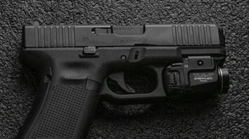A close-up image of a handgun resting on a textured surface
