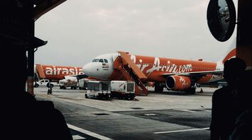 AirAsia aircraft at boarding gate with overcast skies