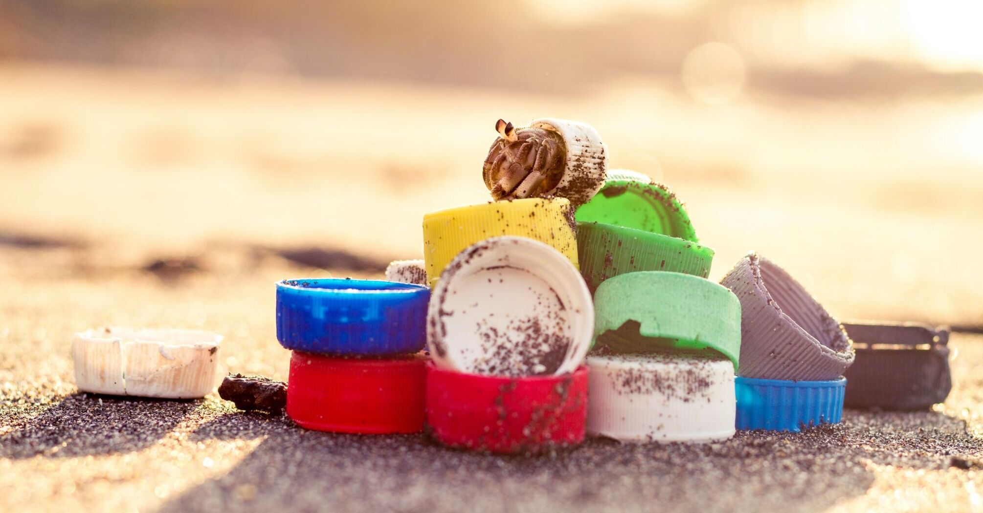 A collection of colorful plastic caps and other small plastic items washed up on a sandy beach