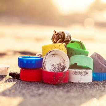 A collection of colorful plastic caps and other small plastic items washed up on a sandy beach