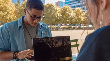 Man and woman sitting while using macbook pro