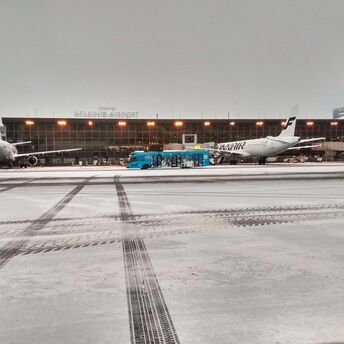 View of Helsinki Airport with Finnair planes and a service bus on a tarmac