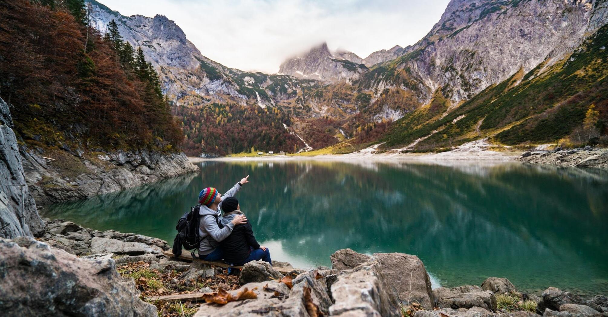 Two people are sitting in the mountains near the lake