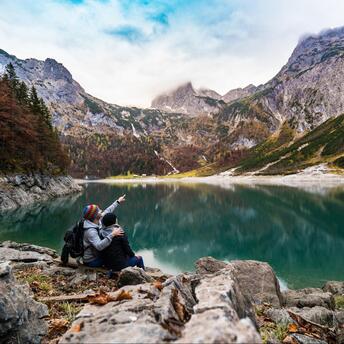 Two people are sitting in the mountains near the lake