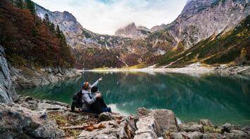 Two people are sitting in the mountains near the lake