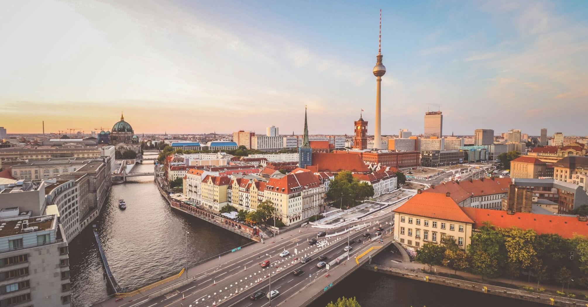 Aerial view of Berlin cityscape at sunset with the Spree River, iconic TV Tower, and distinctive buildings