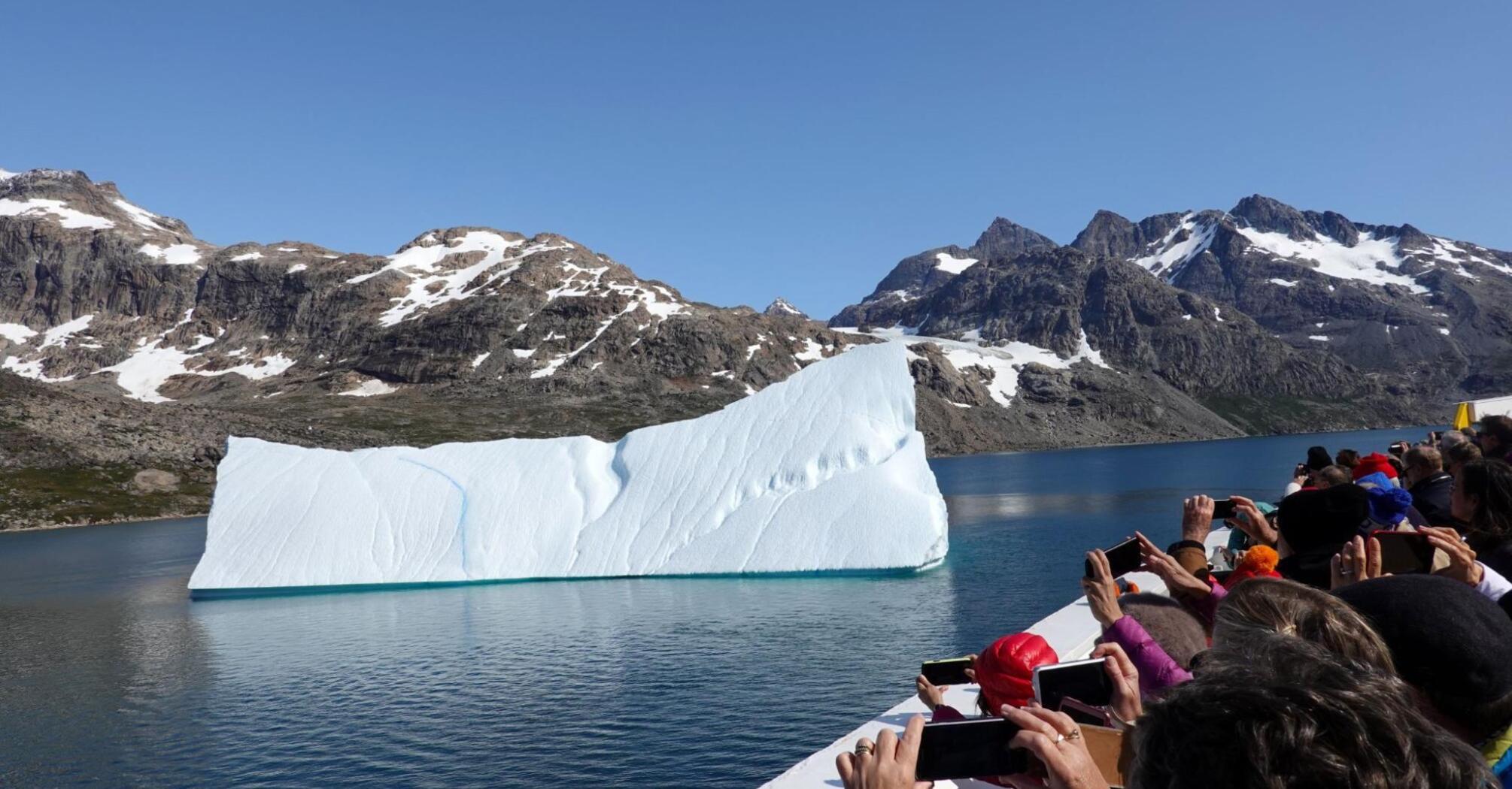 Tourists from a cruise ship photographing an iceberg