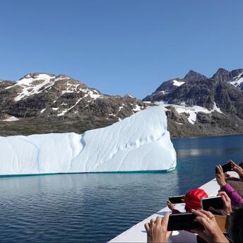 Tourists from a cruise ship photographing an iceberg