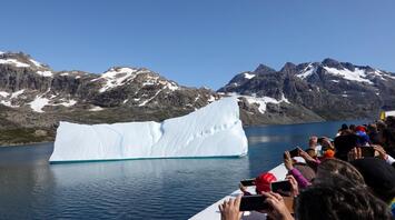 Tourists from a cruise ship photographing an iceberg