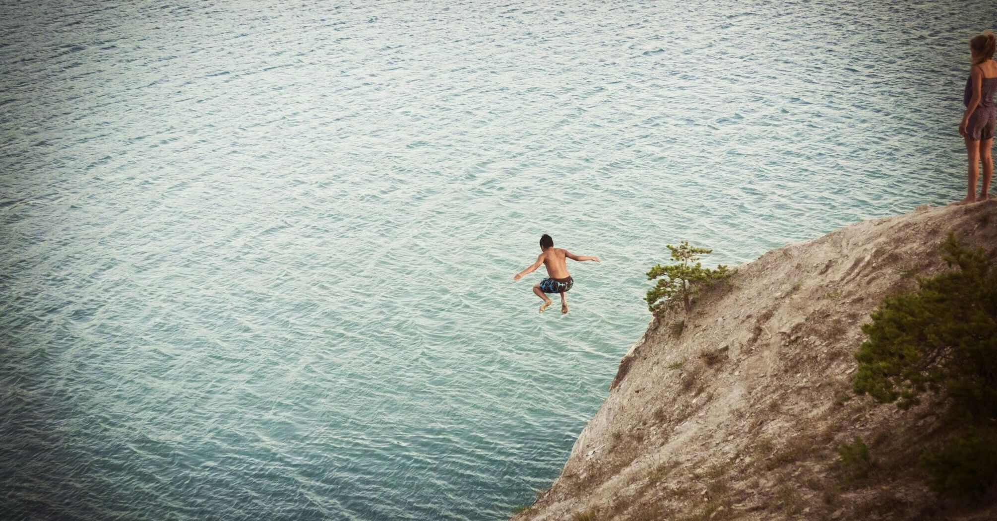 Boy jumping on body of water
