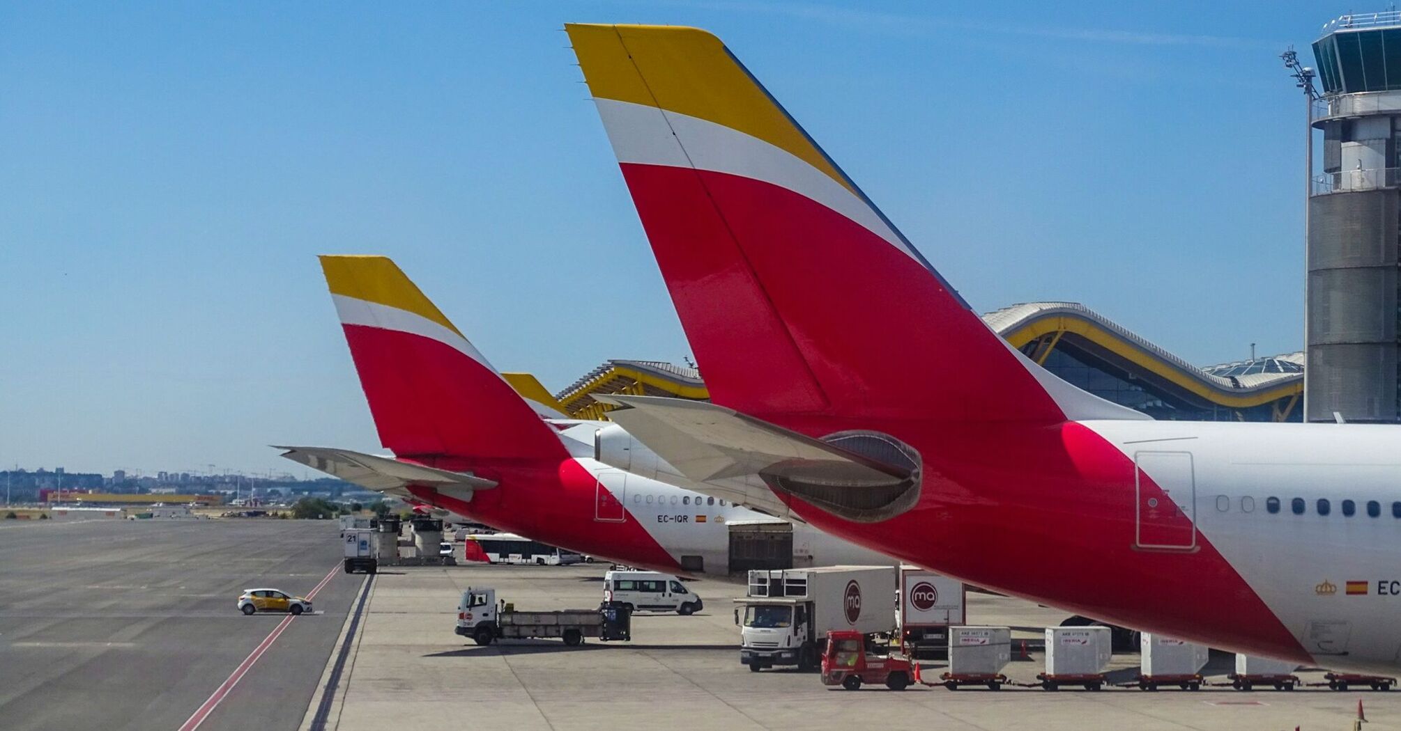 Iberia planes lined up at an airport, with distinctive red and yellow tail fins