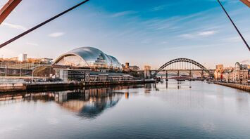 Sunset view of Newcastle cityscape featuring the iconic Gateshead Millennium Bridge and the modern