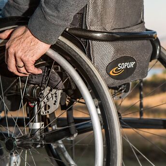 Close-up of a person's hand adjusting the wheel of a modern wheelchair