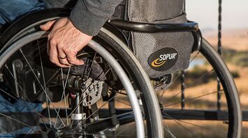 Close-up of a person's hand adjusting the wheel of a modern wheelchair