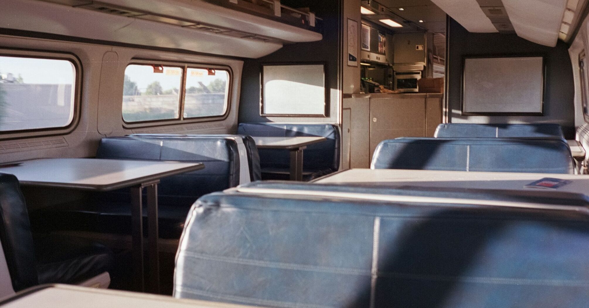 Interior of an Amtrak train showing empty blue seats and tables in the café car