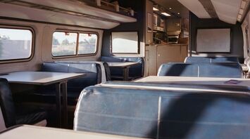 Interior of an Amtrak train showing empty blue seats and tables in the café car