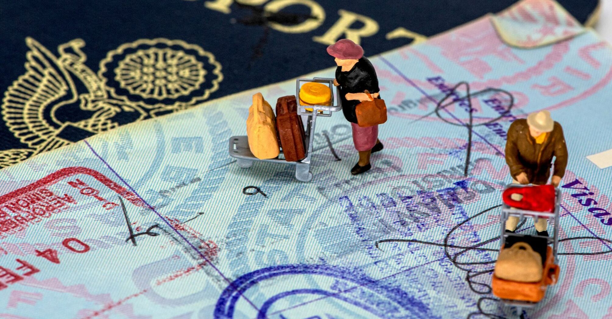 Miniature figures on a passport with travel stamps and visas, depicting travelers with luggage