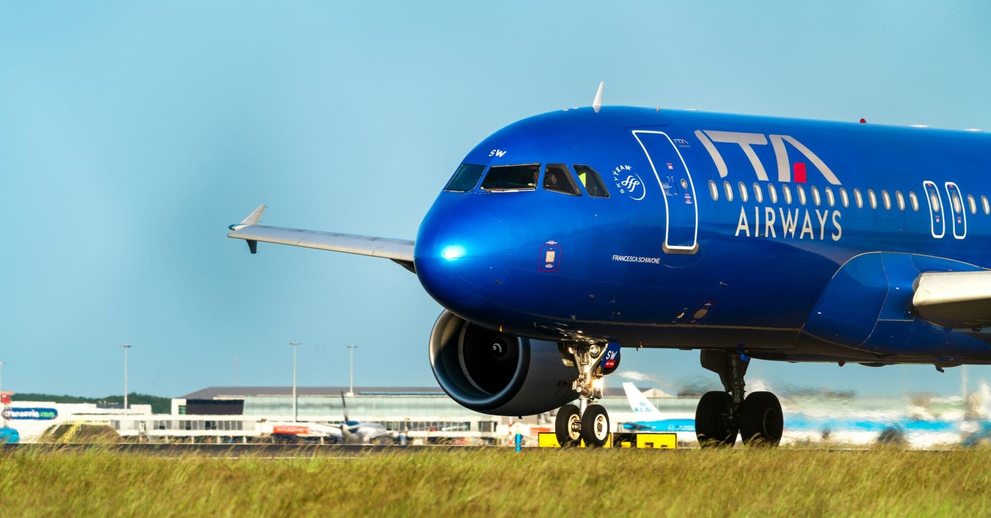 ITA Airways blue airplane taxiing on runway at airport