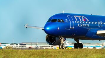 ITA Airways blue airplane taxiing on runway at airport