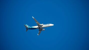 A blue and white airplane flying in a blue sky