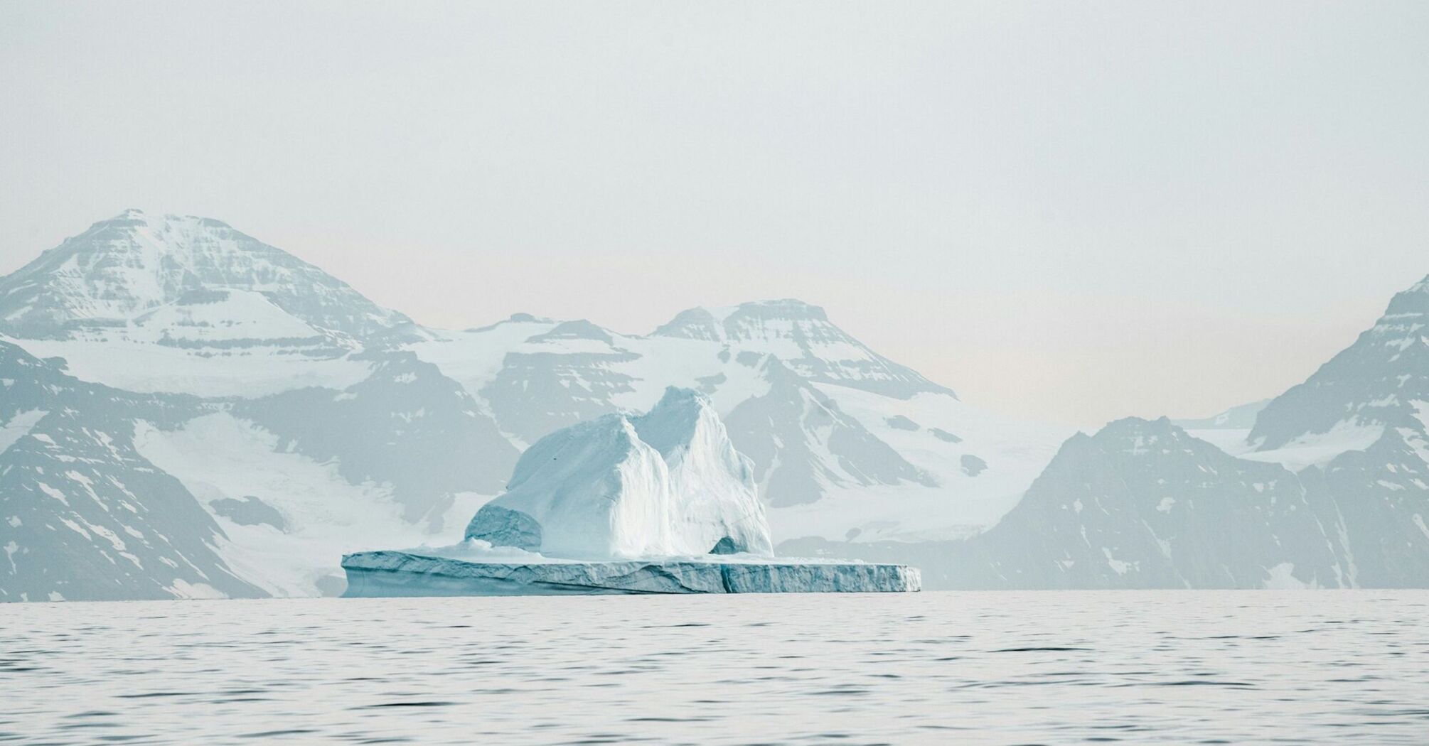 Serene Arctic landscape with an iceberg and snow-capped mountains