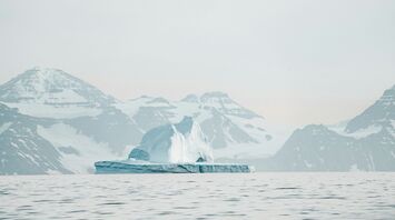 Serene Arctic landscape with an iceberg and snow-capped mountains