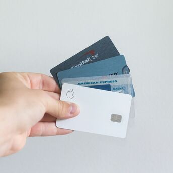 Hand holding several credit cards including American Express and Capital One
