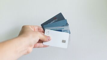 Hand holding several credit cards including American Express and Capital One