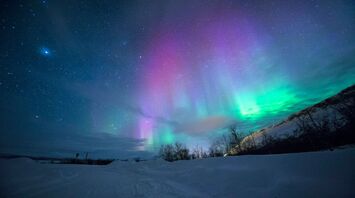 Northern lights over snow capped mountian