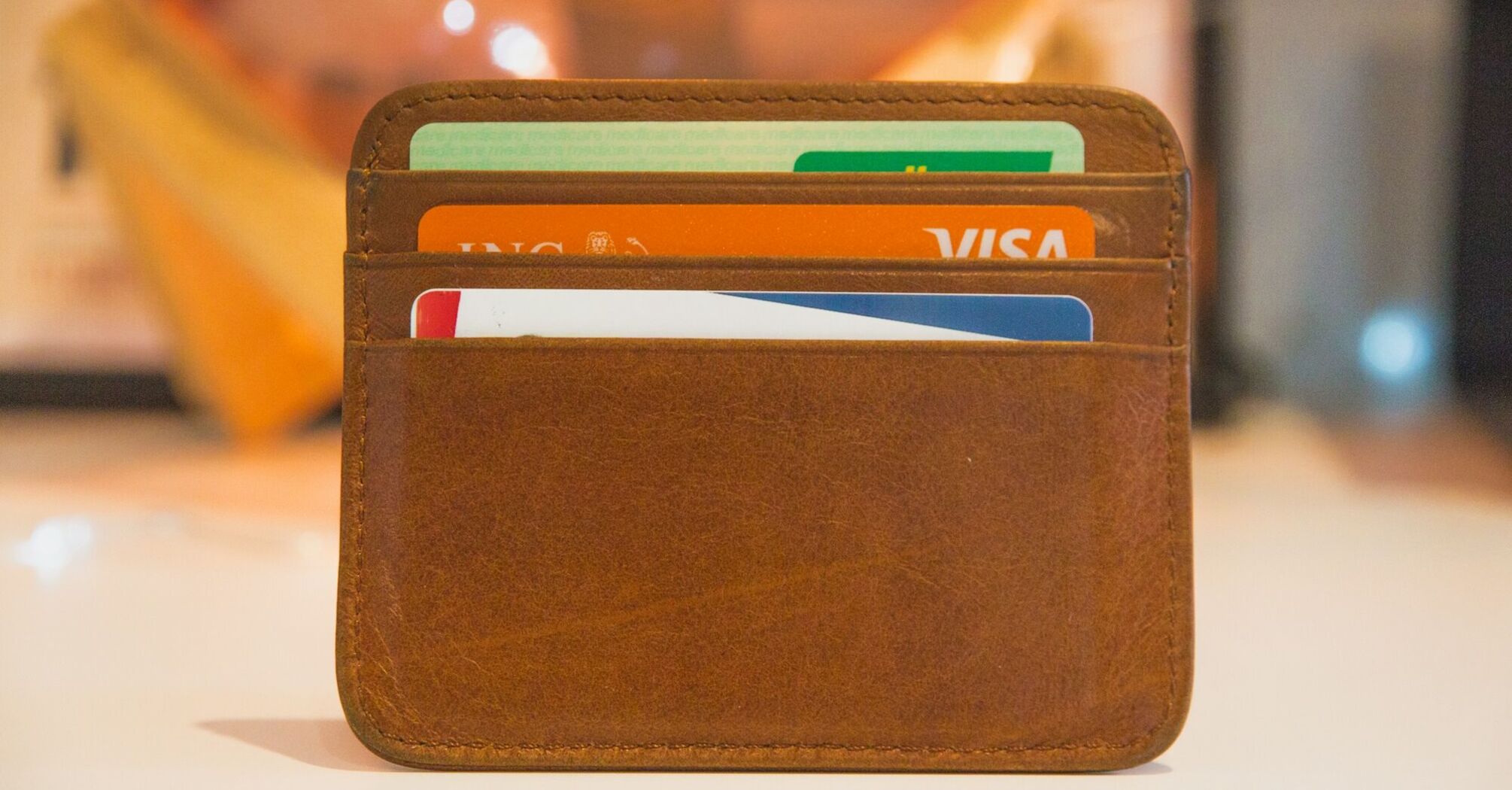 A brown leather wallet holding multiple credit cards