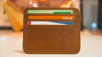 A brown leather wallet holding multiple credit cards