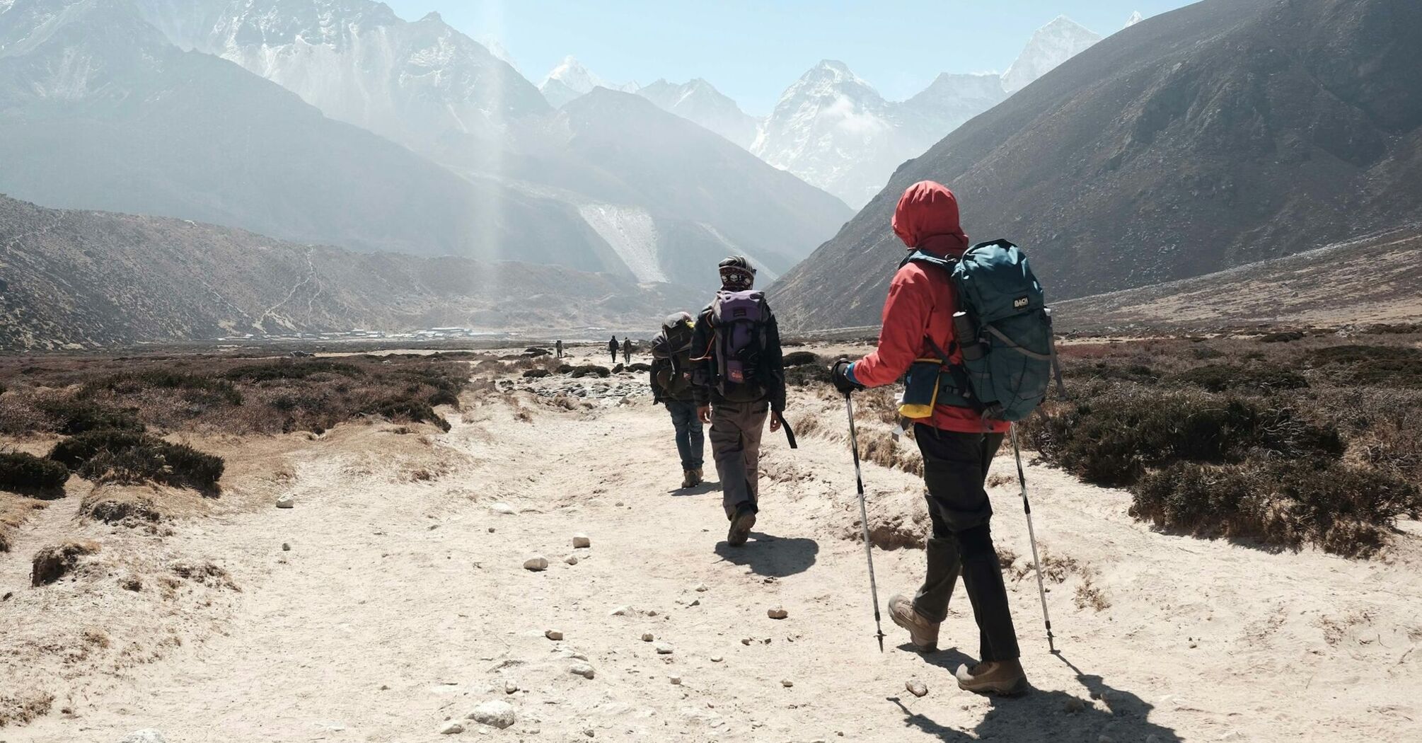 Group of climbers trekking through a valley towards Everest with mountains in the background 