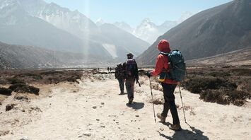 Group of climbers trekking through a valley towards Everest with mountains in the background