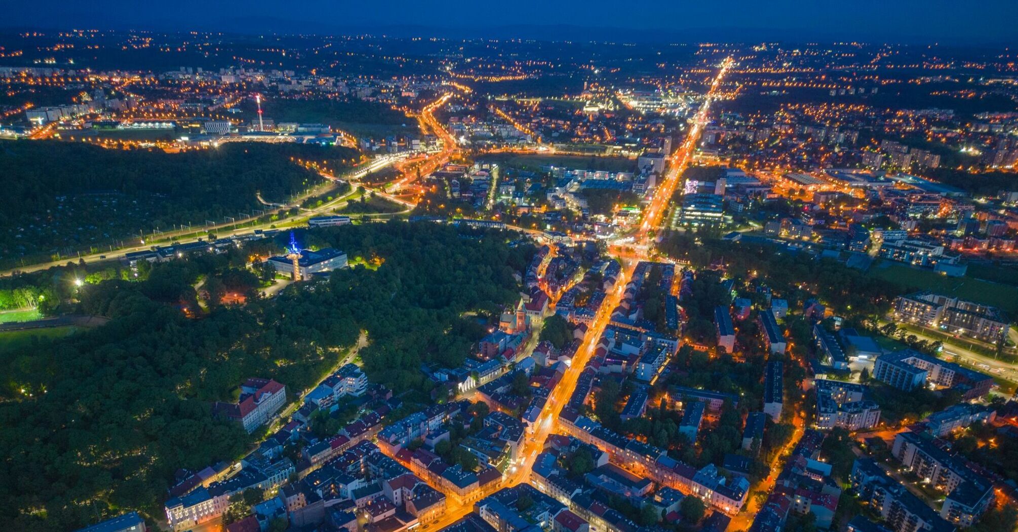 Aerial view of Krakow at night, showcasing illuminated streets and city layout