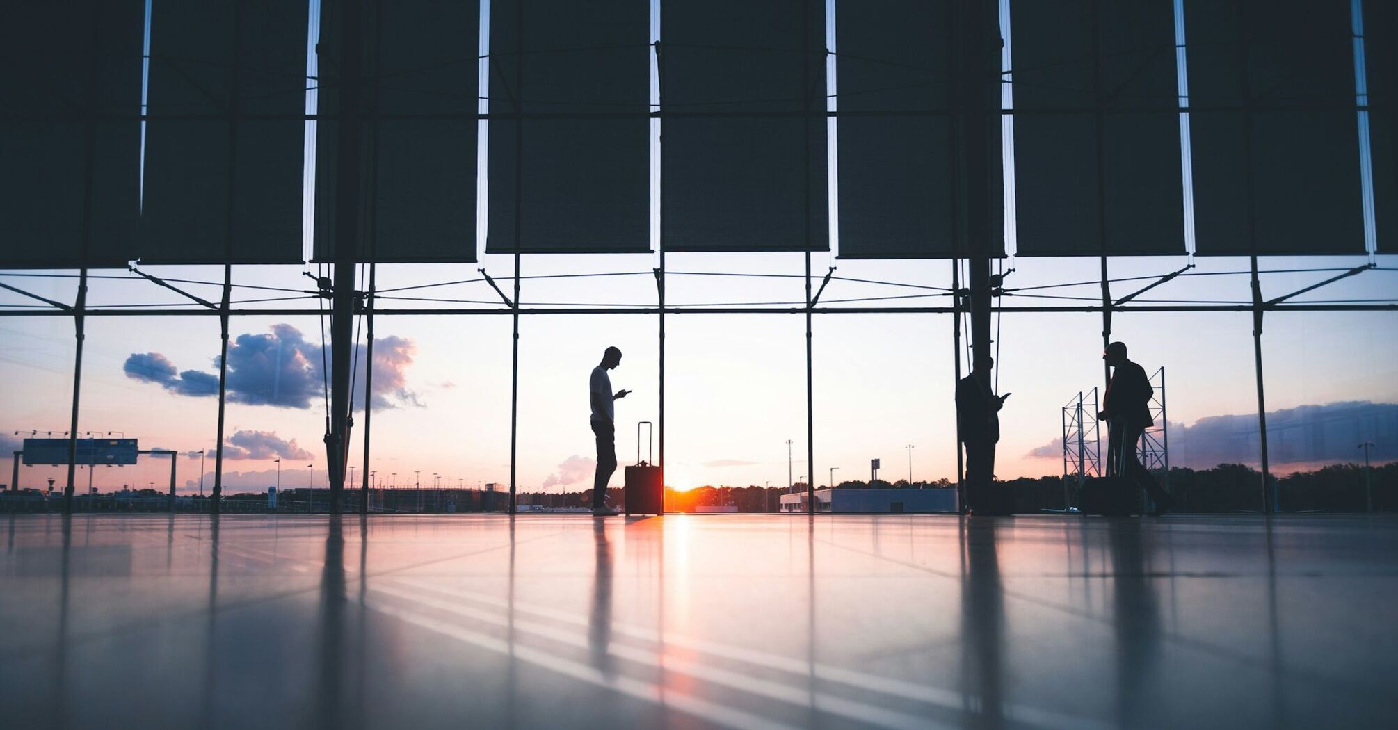 Silhouettes of travelers at an airport during sunset
