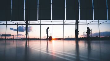 Silhouettes of travelers at an airport during sunset