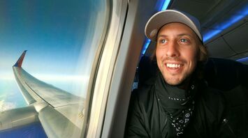 Smiling man enjoying a flight with a view of airplane wing through window