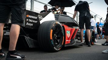 Racing car on the track, surrounded by the team and spectators