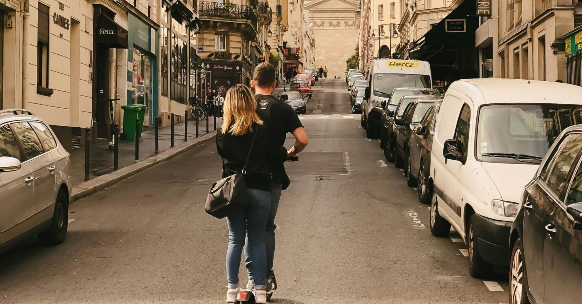 Man and woman riding kick scooter in Paris