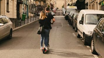 Man and woman riding kick scooter in Paris