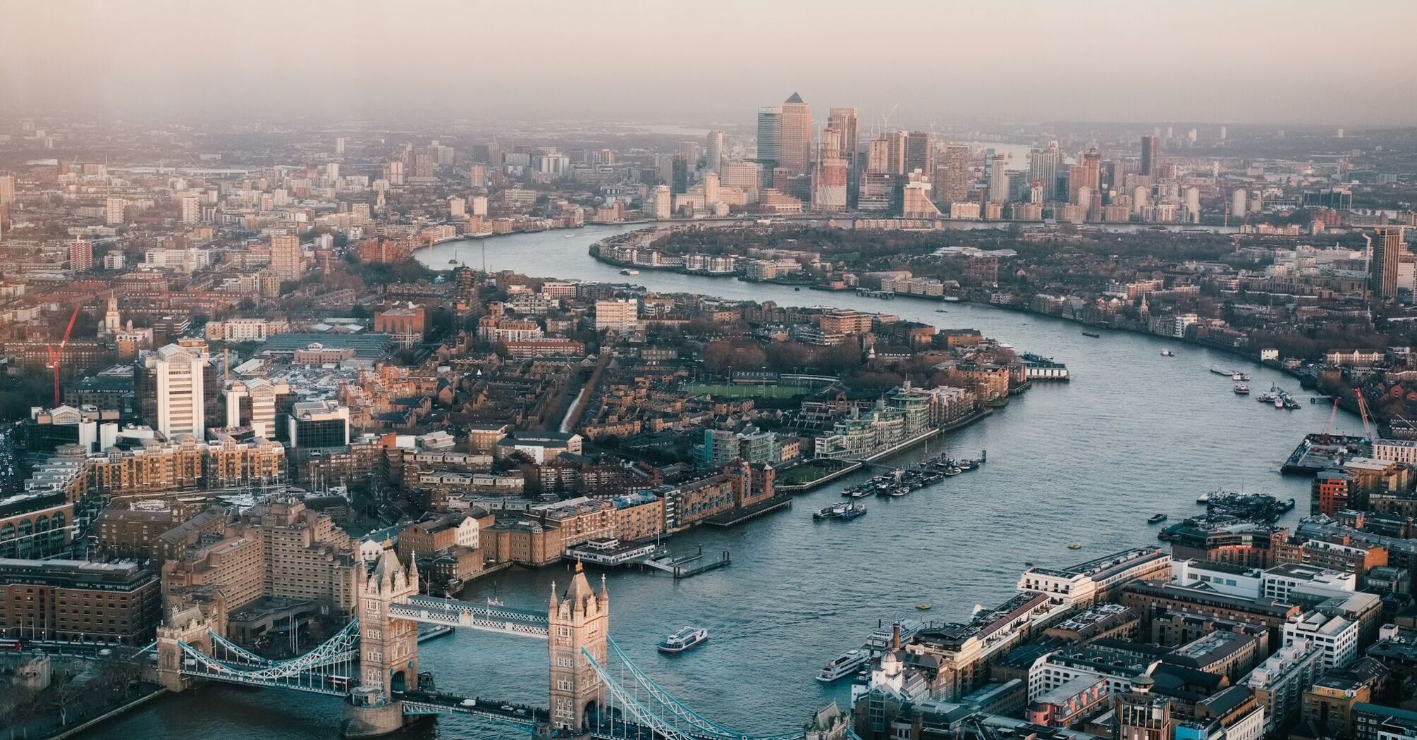 Aerial view of London showcasing the River Thames and iconic landmarks such as the Tower Bridge and Canary Wharf
