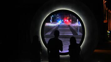 Passers-by look into the portal connecting two cities
