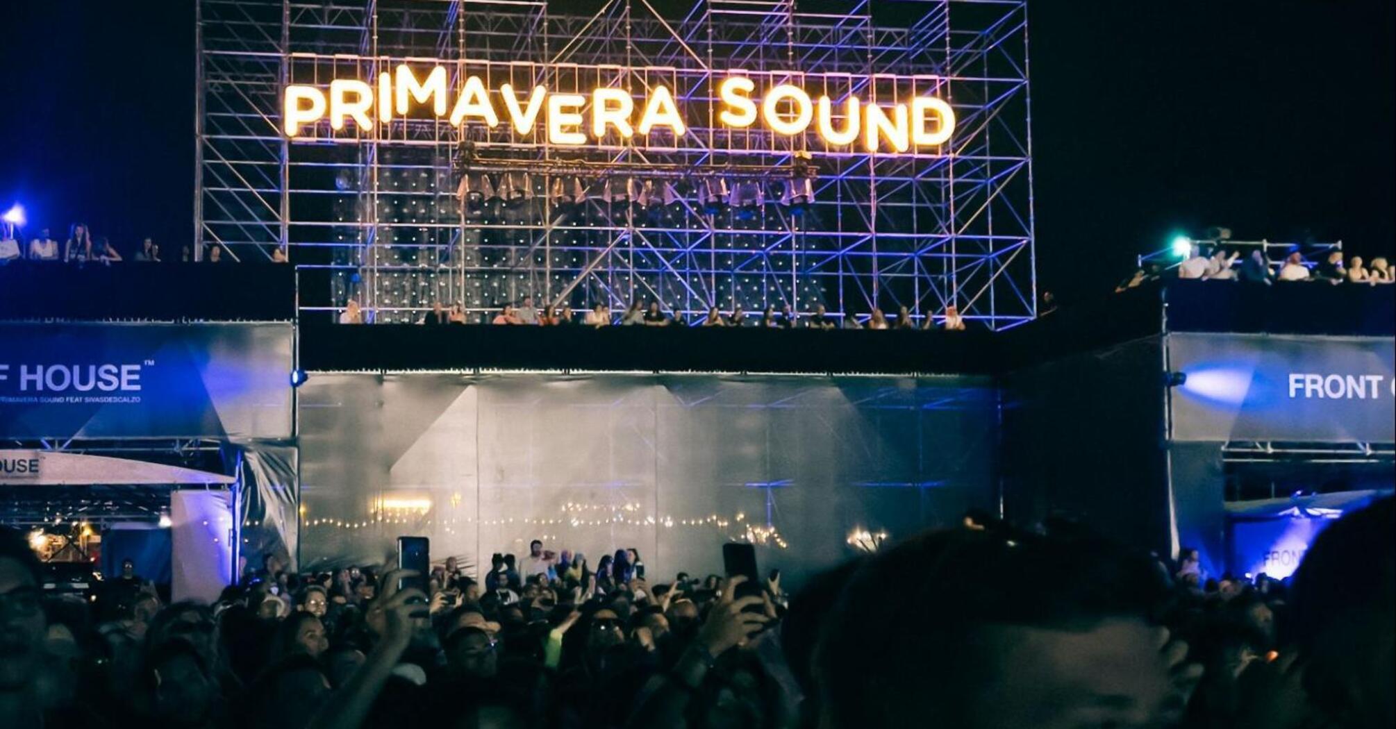 A large crowd of people in front of a stage with a sign