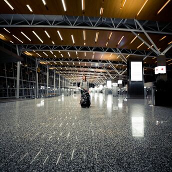 A solitary traveler with a rolling suitcase walks through the spacious, well-lit terminal of Calgary International Airport