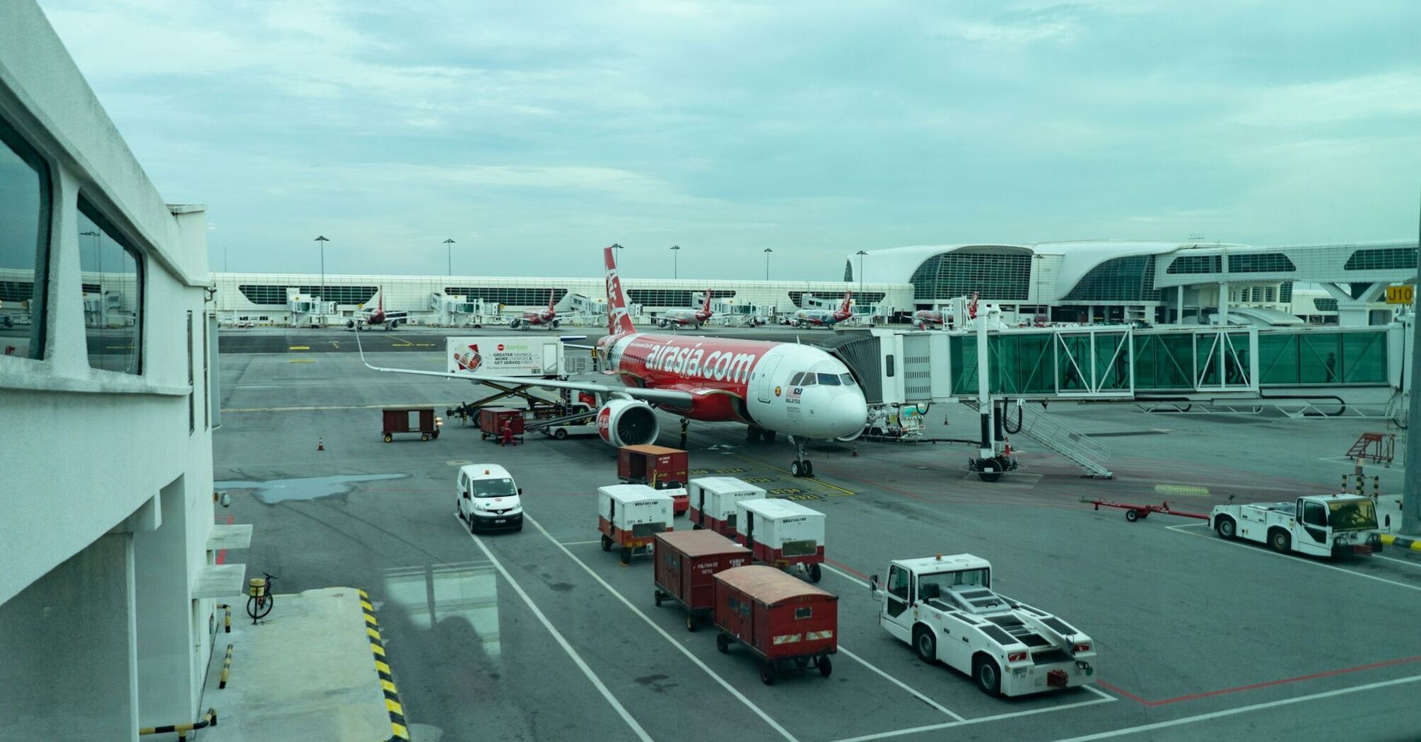 AirAsia aircraft parked at the airport gate, with ground support vehicles nearby