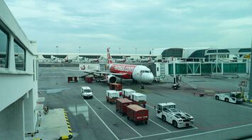 AirAsia aircraft parked at the airport gate, with ground support vehicles nearby